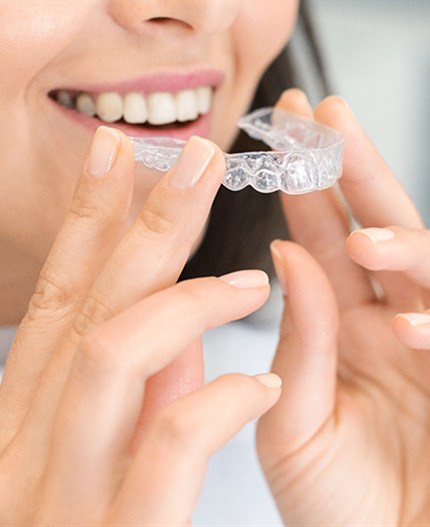 Patient holding clear Invisalign aligners in Pasadena