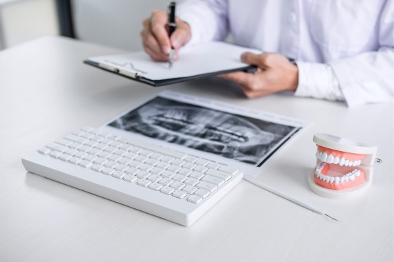 Doctor or dentist working with patient tooth x-ray film, model and equipment used in the treatment